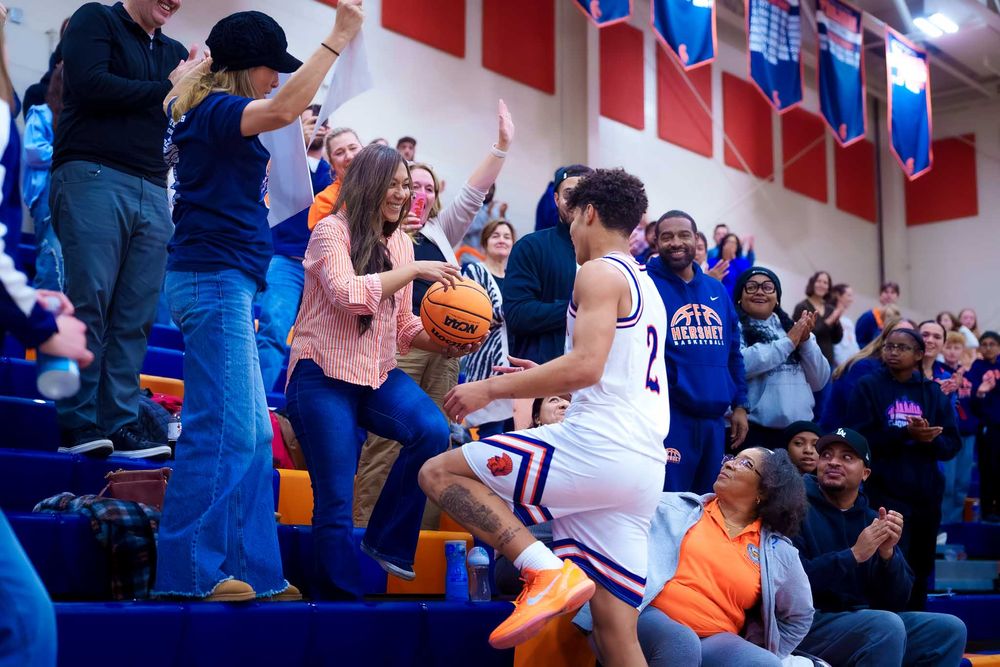 Cam Sweeney climbs into the stands to celebrate with fans after his 1,000th point at Hershey High School basketball game.