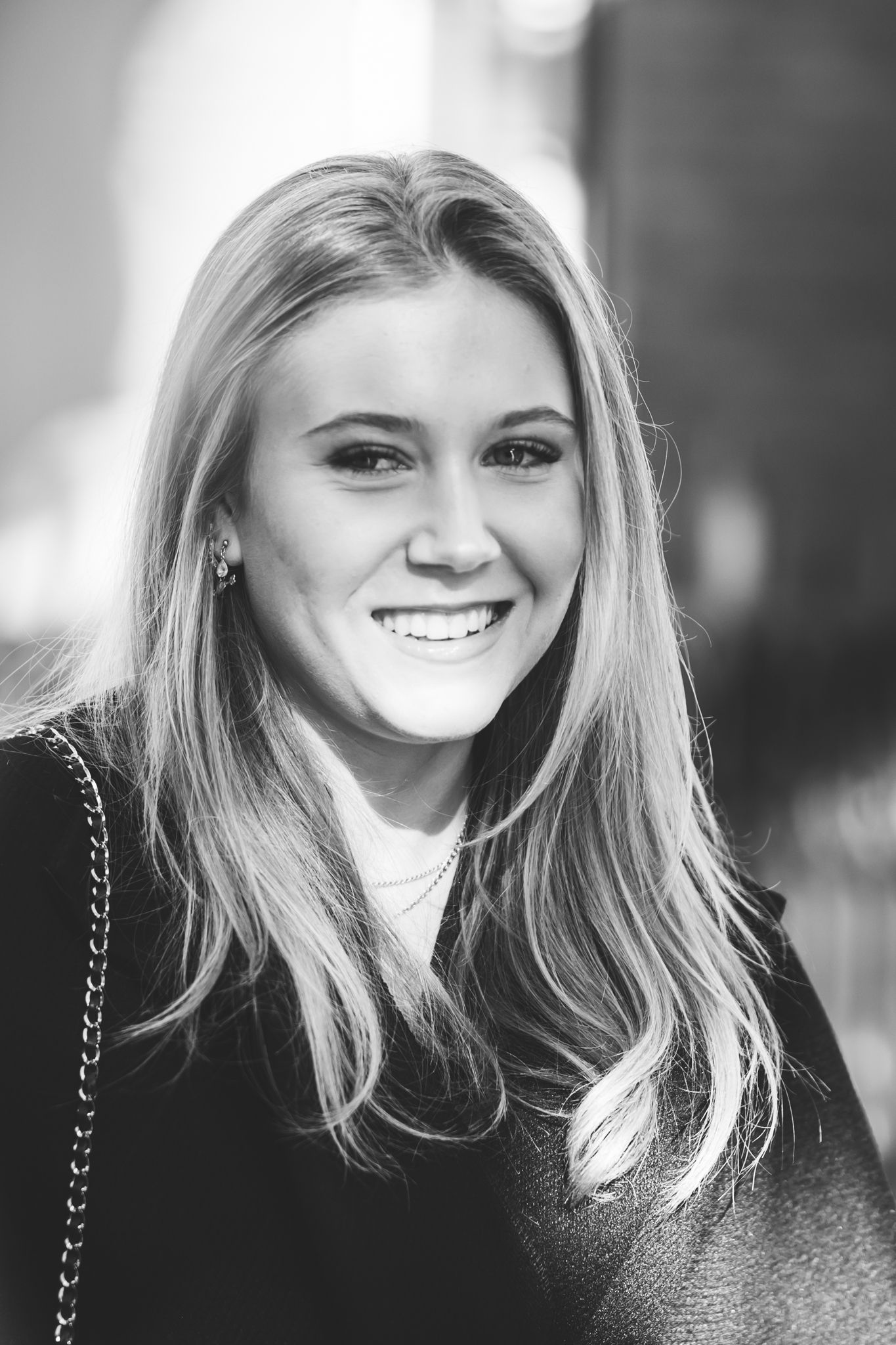 Black and white portrait of a smiling young woman with long blonde hair wearing a dark top.