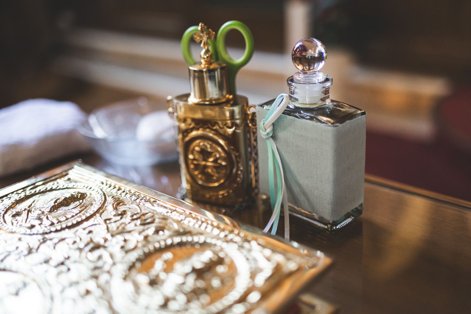 Vintage perfume bottles and ornate silver box arranged on reflective surface in soft natural lighting.