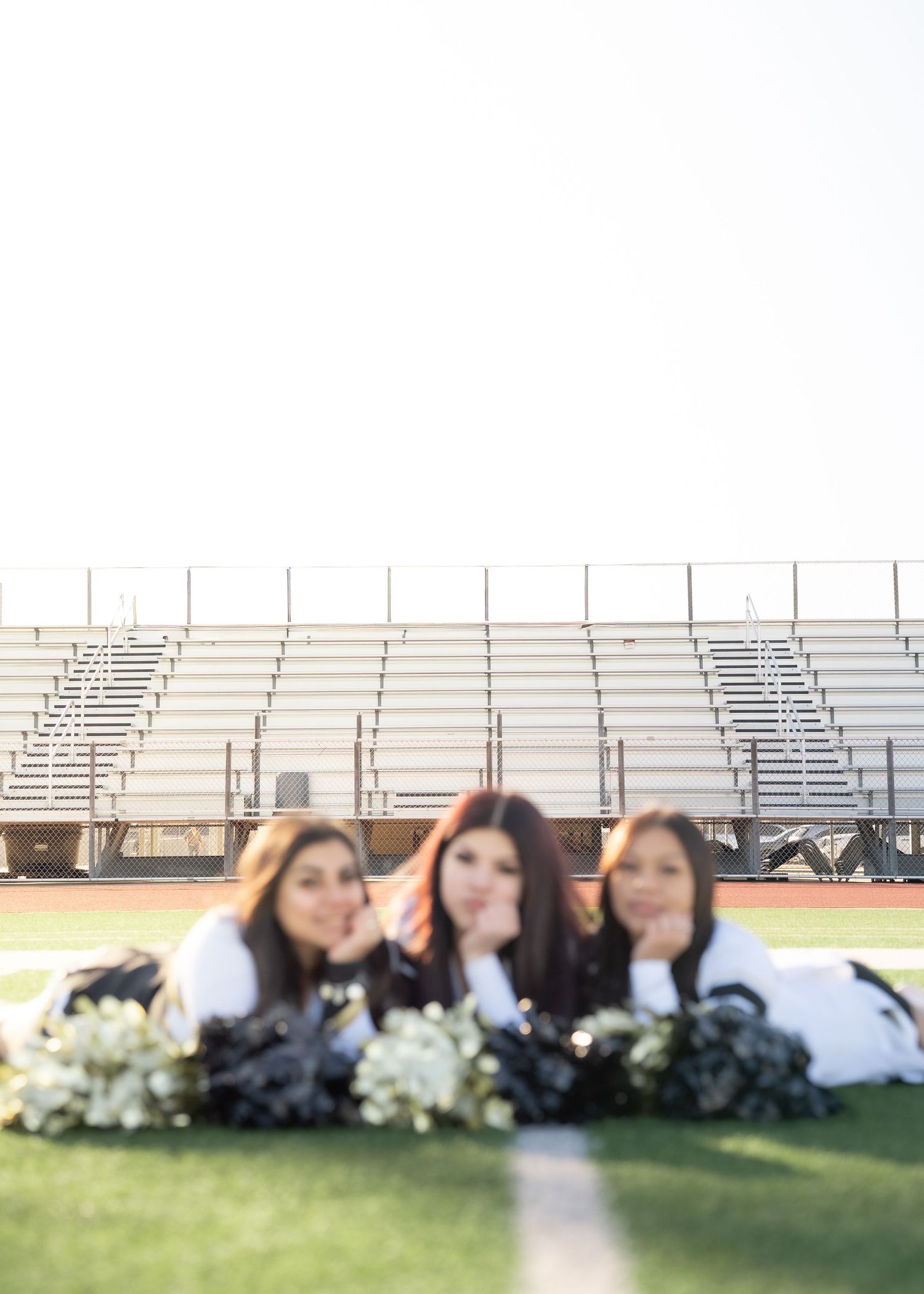 Cheerleaders tossing pom-poms in the air during outdoor group portrait