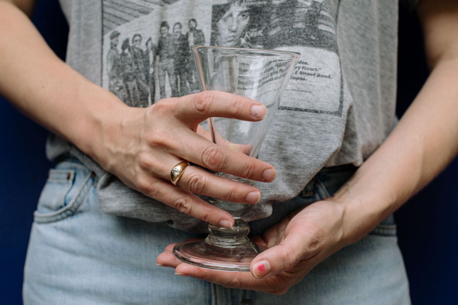 Hands holding vintage black and white portrait photographs against a dark blue background with yellow floral pattern.