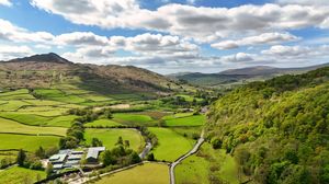 Stunning landscape of rolling hills with patchwork fields and mountain backdrop.
