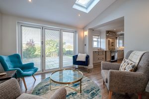 Modern living room with skylight, sliding glass doors, turquoise accent chair and circular glass coffee table.