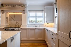 Bright white kitchen with marble countertops, shaker cabinets and stainless steel appliances.