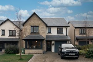 Contemporary stone and render detached house with black car parked in driveway.