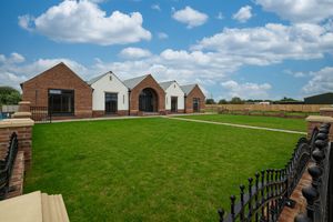 Panoramic view of brick and white residential buildings with a paved walkway leading through green lawns.