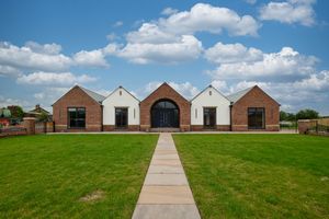 Wide angle view of symmetrical brick buildings connected by a concrete pathway under blue skies.