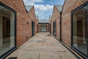Modern brick buildings with glass facades forming a corridor with stone paving.