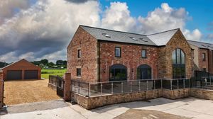 Panoramic view of brick buildings with modern architectural features under bright blue sky.