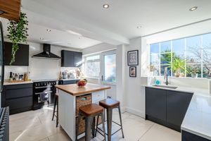 Modern kitchen with black cabinets, wood countertops, and a central island with bar stools.