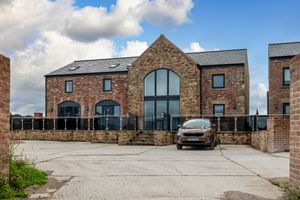 Panoramic shot of brick buildings with gravel parking area and modern design elements.