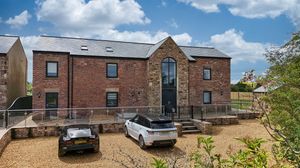 Wide panoramic view of brick buildings with parked cars and modern architectural features.
