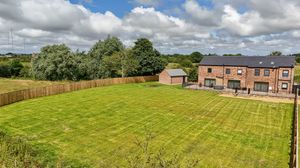 Panoramic landscape view of residential development with green fields and trees in background.