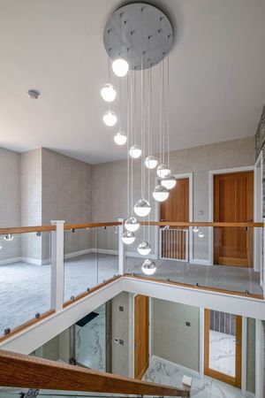 Elegant stairwell featuring a cascading spiral chandelier with glass orbs and wooden handrails.