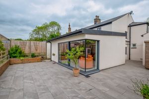 Contemporary house extension with large sliding glass doors opening onto a grey stone patio.