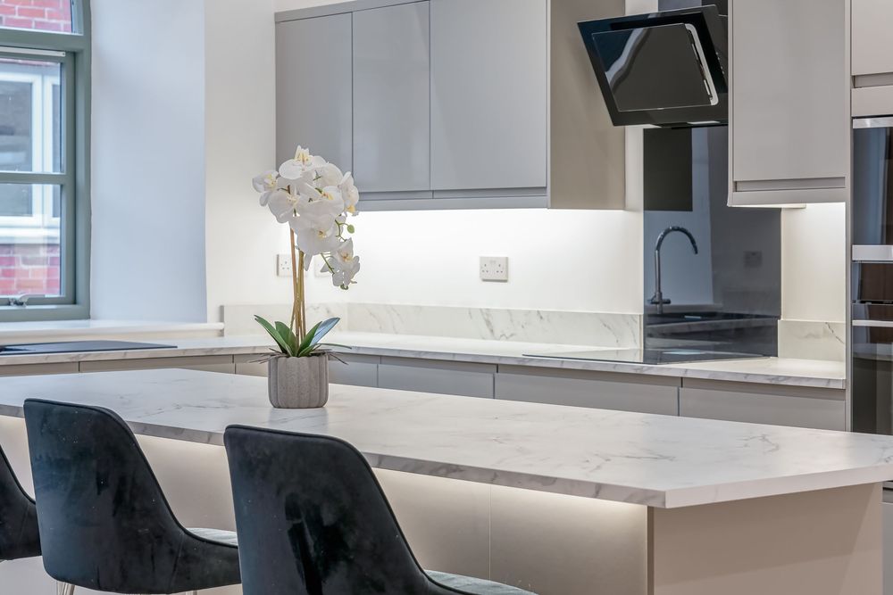 Contemporary white kitchen featuring minimalist design with marble countertops and sleek cabinetry.