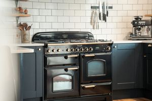 Black vintage-style range cooker with multiple ovens and gas hobs against white tile backsplash.