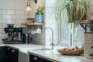 Modern kitchen counter with white subway tiles, hanging plants and coffee station.