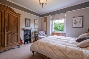 Elegant bedroom interior with wooden furniture, neutral tones, and natural light streaming through windows.