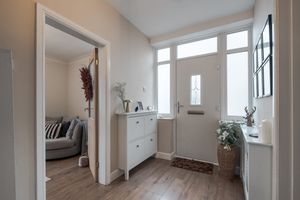 Bright entrance hallway with white furniture, wooden flooring and glass door.
