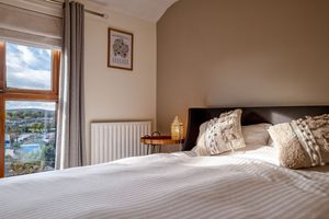 Spacious bedroom with panoramic windows showcasing coastal views and contemporary furnishings.