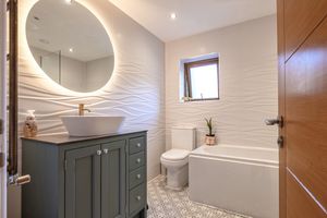 Modern bathroom interior with curved archway, grey cabinets, and white textured walls.