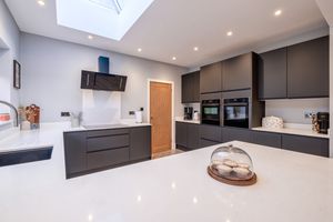 Contemporary white kitchen with dark cabinets, recessed lighting, and sleek modern appliances.