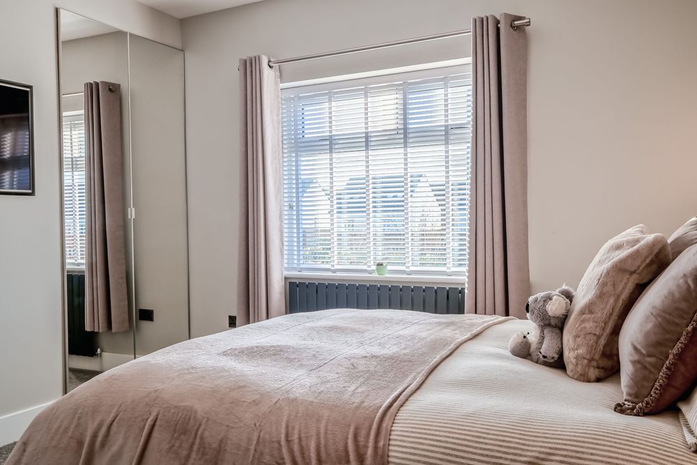 Elegant bedroom with neutral tones, featuring plush bedding and modern window treatments.