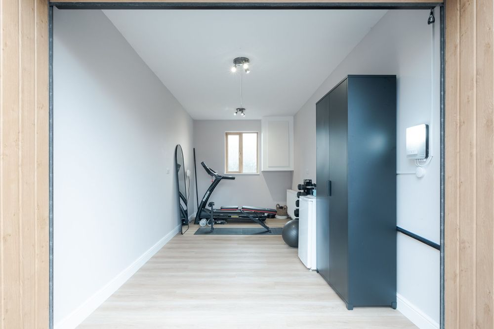Home gym setup in a bright white room with exercise equipment and storage.