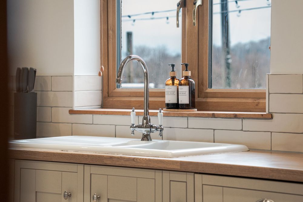 Country-style kitchen with cream cabinets, wooden accents, and natural light from windows.