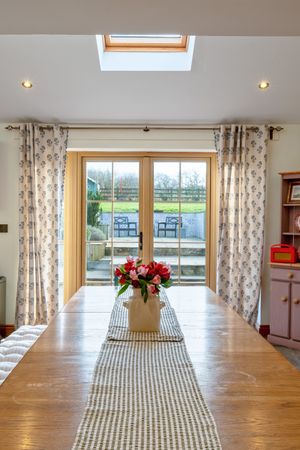 Bright dining area with wooden table, skylights, and large windows overlooking countryside views.