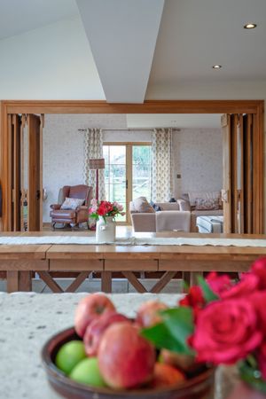 Living room view through wooden folding doors with fresh flowers and fruit in foreground.