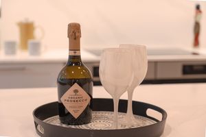 Bottle of prosecco and frosted glasses arranged on dark serving tray.
