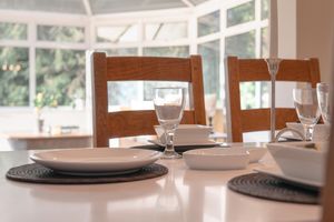 Elegant dining table setting with wooden chairs and place settings on white tablecloth.