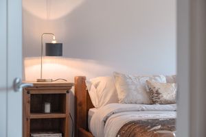 Contemporary bedroom with wooden bed frame and natural lighting from large windows.