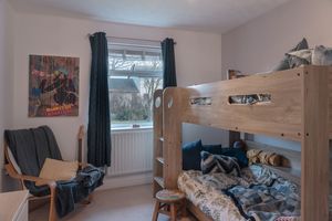 Children's bedroom with bunk beds and dark curtains against white walls.