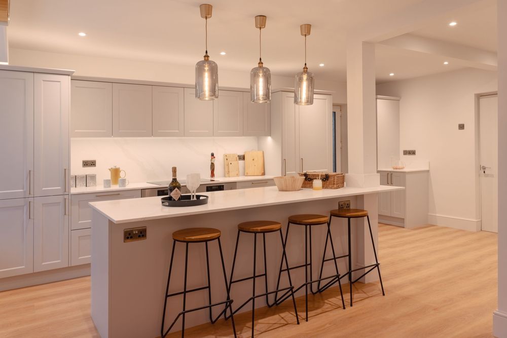 Sleek modern kitchen with gray cabinets, pendant lights, and breakfast bar with wooden stools.