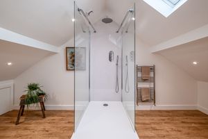 Contemporary bathroom with glass shower enclosure and wooden flooring.