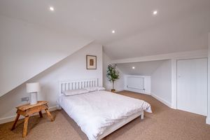 Bright bedroom with recessed lighting and neutral carpeting.