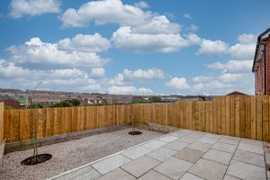 Large paved patio area with wooden fence under blue sky with white clouds.