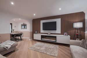 Contemporary living room featuring wood-paneled media wall, modern furniture, and recessed lighting.