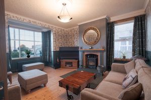Cozy living room with traditional furnishings, wall-mounted TV, and decorative wallpaper.