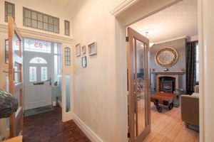 Long hallway with hardwood floors, white walls, and natural light from multiple windows.