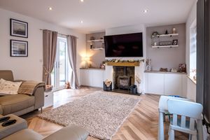 Elegant living room with wooden floors, built-in storage, and wall-mounted TV above a traditional fireplace.
