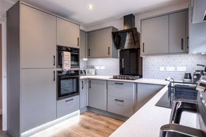 Contemporary grey kitchen with white countertops, integrated appliances and wood flooring.