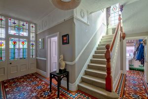 Grand entrance hallway with stained glass windows and patterned tile flooring.