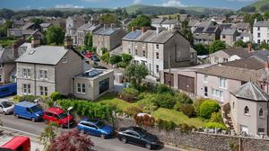 Aerial view of a residential neighborhood with traditional stone houses and parked cars on a hillside.