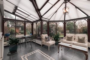Modern conservatory with glass ceiling and comfortable seating area bathed in natural light.
