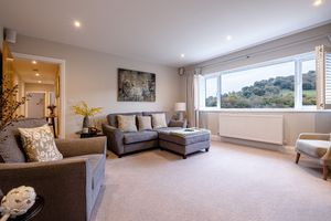 Bright living room with grey sectional sofa, large window offering hillside views, and modern decor.