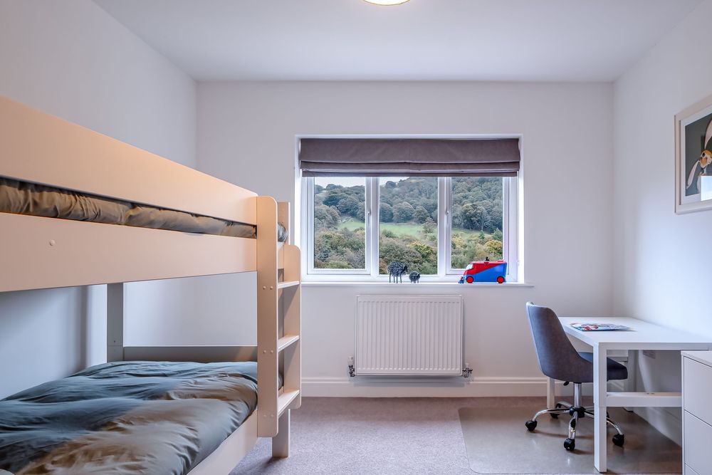 Minimalist white bedroom interior with window and basic furnishings.